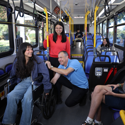 Bus operator assisting person in wheelchair on bus